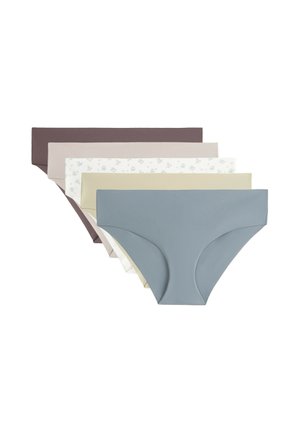 Femme portant un sous-vêtement style hipster beige clair sans couture, visible de la taille aux hauts des cuisses sur un fond clair.