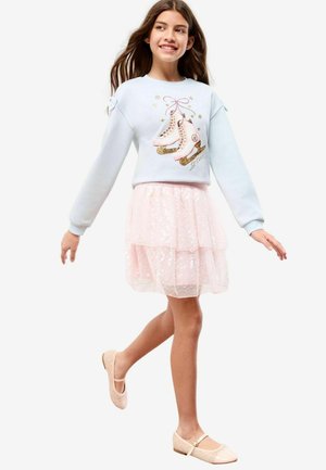 Hellblauer Sweatshirt mit Skate-Grafik, kombiniert mit einem pinken, gestuften Rock mit Pailletten und geschlossenen Ballerinas.