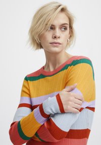 Pull rayé côtelé avec un mélange de couleurs jaune, rouge, vert et lavender. Le design comprend des manches longues avec des poignets serrés.