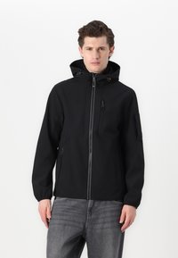 Casaco preto com capuz, apresentando um fecho frontal com zíper, múltiplos bolsos com zíper e um acabamento suave e mate. Inclui cordões ajustáveis e punhos.
