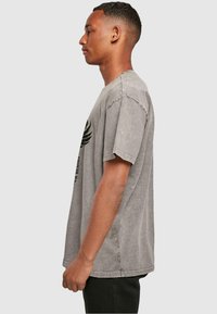 Grijze katoenen T-shirt met korte mouwen, een ronde halslijn en een gedrukt ontwerp op de voorkant met een grafisch element en tekst.