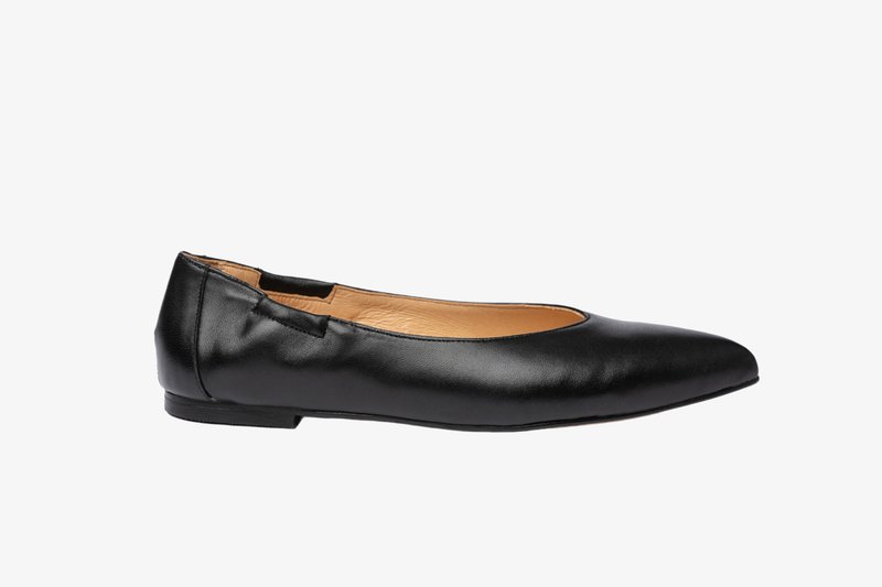 Bailarina de cuero negro con punta redondeada, textura suave, tacón bajo y detalles recortados en los laterales. El interior es beige.