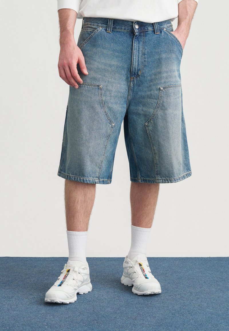 Denimshorts i lys blå vask med store forlommer og et lige snit. Kombineret med hvide sneakers og midterlange sokker.