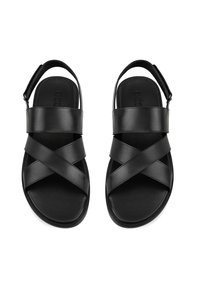 Schwarze Ledersandalen mit Kreuzriemen, einem hinteren Fersenriemen und flachen Sohlen. Glatte Textur und minimalistisches Design.