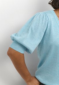 Light blue knitted sweater with puffed short sleeves and a V-neckline. Soft texture and fitted cuffs.