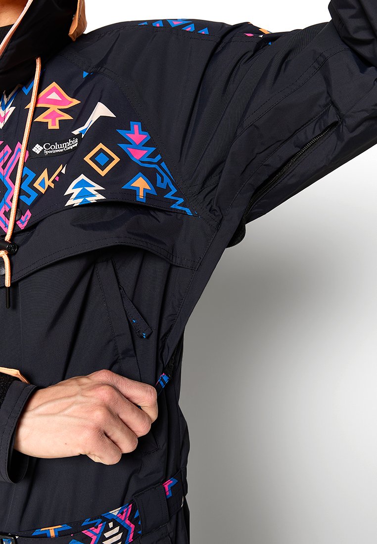 Czarna kurtka z kolorowymi wzorami geometrycznymi w odcieniach różu, niebieskiego i pomarańczowego. Zawiera kieszeń na zamek i regulowany kaptur.