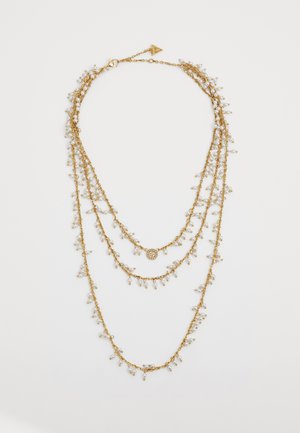 Collana a strati dorata con tre catene, caratterizzata da delicati gruppi di piccole perline bianche e un pendente decorativo centrale.