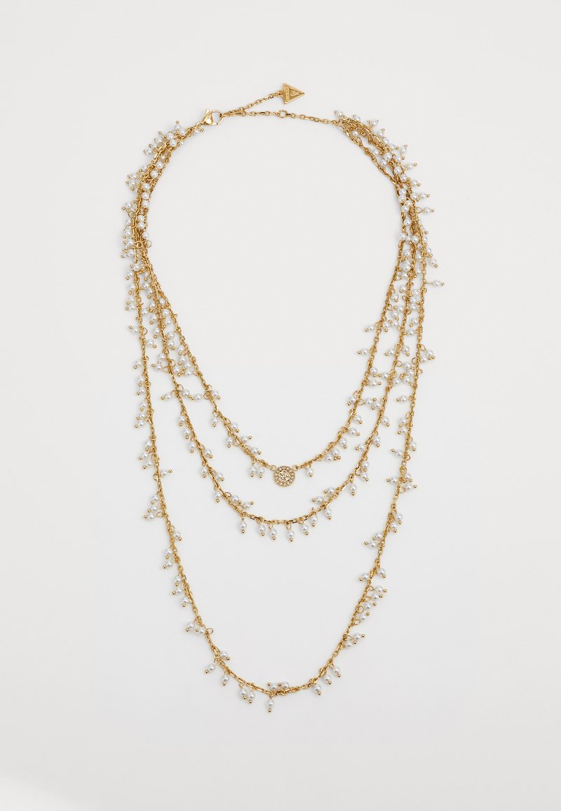 Gouden gelaagde ketting met drie kettingen en delicate clusters van kleine witte kralen, evenals een centraal decoratief hangertje.