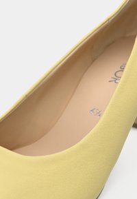 Κίτρινο δερμάτινο παπούτσι με στρογγυλεμένη μύτη, με ομαλή υφή και διακριτική λάμψη. Στο εσωτερικό εμφανίζεται η ένδειξη μεγέθους 41/4.