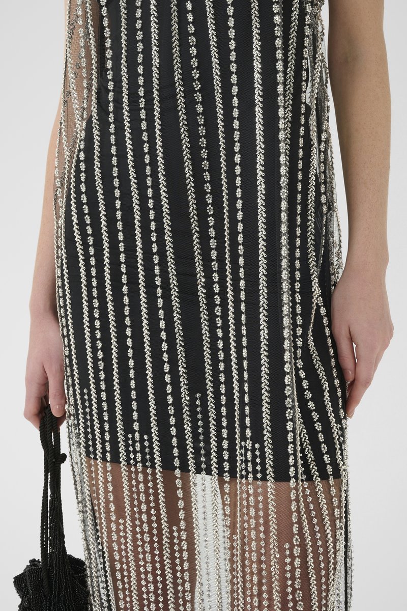 Black dress with silver beaded fringe design and mesh overlay. Features vertical lines of beads and a fitted silhouette. Includes a black bag.