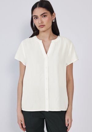 Kurze weiße Bluse mit V-Ausschnitt, durchgehender Knopfleiste und glatter Stoff. Sie verfügt über einen lockeren Schnitt und einen subtilen Glanz.