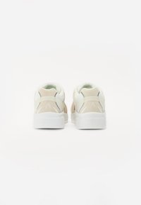 Sneakers met een combinatie van beige en witte materialen, met een gestructureerde suède achterkant, een mesh-tong en dikke witte zolen.