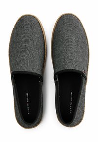 Grå stof slip-on sko med en struktureret overflade, kontrasterende brun sål og sort indvendig. Har logo synligt indeni hver sko.