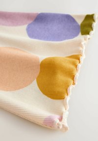 Bomullstyg med ribbad textur som har stora, växlande pastellcirklar i rosa, lila, gult och oliv, med vågiga kanter.