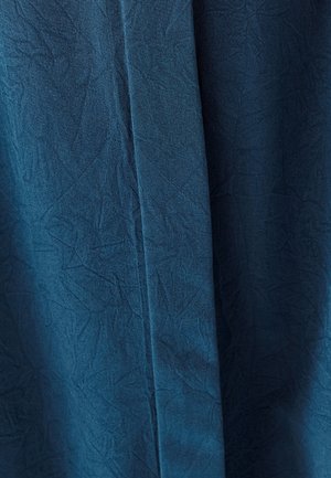 Kankaita syvissä sinisessä, jossa on ryppyinen ulkonäkö. Materiaali esittää hienoja kuvioita ja laskeutuu sujuvasti.