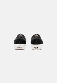 Black corduroy sneakers with white rubber soles. Features stitched accents and a logo on the heel. Low-top design with round toe.