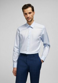 Light blue long-sleeve shirt with button-up front, classic collar, and smooth fabric, paired with navy plaid trousers featuring subtle check pattern.