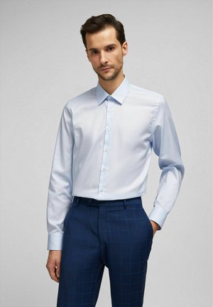 Lichtblauw overhemd met lange mouwen, knoopsluiting aan de voorkant, klassieke kraag en een gladde stof, gecombineerd met marineblauwe geruite broek met subtiele ruitpatronen.
