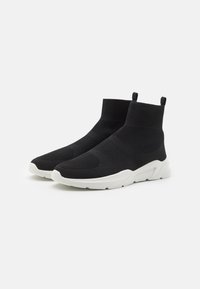 Sneakers con calzini alla caviglia in maglia nera, con una parte superiore testurizzata, colletto elastico e suola in gomma bianca. Presentano una suola imbottita per il comfort.