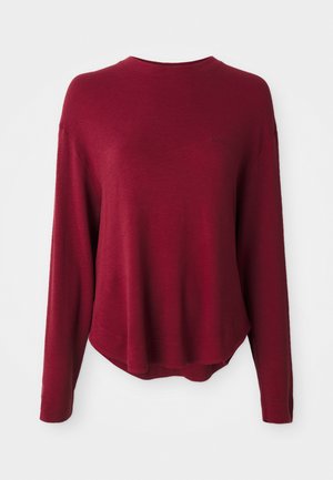 Burgundy långärmad tröja med rund halsringning, ribbat mönster och en lätt böjd nederkant. Minimalistisk logotypdetalj på framsidan.