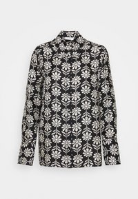 Camicia nera con un motivo floreale bianco. Ha un collo, chiusura frontale con bottoni e maniche lunghe con taglio dritto.