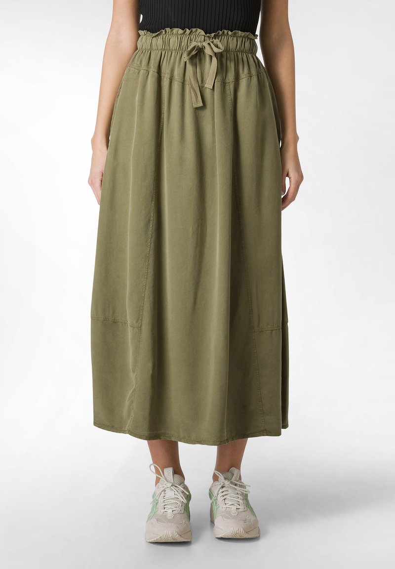 Fustă lungă până la gleznă, de culoare verde măsliniu, fabricată dintr-un material moale, având un brâu elastic cu șnur și cusături laterale discrete. Purtați cu adidași.