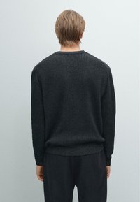 Maglione lavorato a maglia di un grigio scuro con un motivo a coste testurizzato, scollatura rotonda e vestibilità comoda, progettato per il comfort e il calore.