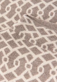 Tappeto strutturato con un motivo geometrico in beige e taupe, con una superficie morbida e pelosa e linee distinte che delineano il design.