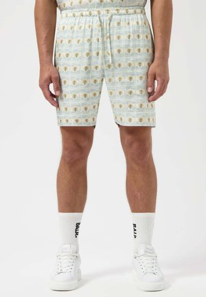 Shorts bleu clair avec un motif répétitif de têtes de lion jaunes. Taille élastique, coupe décontractée et fabriqués en tissu doux.