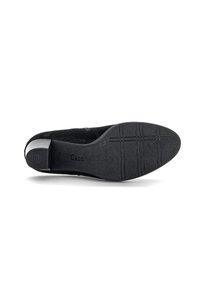 Chaussure en daim noir avec un bout arrondi et un petit talon. La semelle présente des rainures texturées et un logo de marque. Design simple, texture lisse.