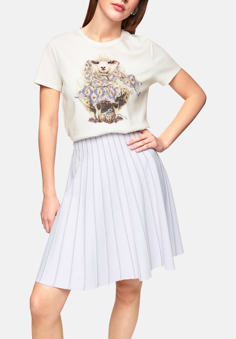 Light cream t-shirt with a sheep graphic, paired with a pleated light gray skirt featuring vertical stripes and subtle shimmer.