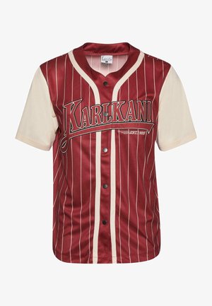 Piros és krém színű, függőleges csíkos póló, gombos elölről, mellkasán logóval. Simább anyagból készült, puha tapintással.