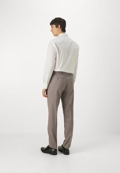 Cămașă albă cu mâneci lungi și mansete cu nasturi, asortată cu pantaloni din material gri deschis, eligibili, și pantofi din piele negri, văzută din spate.