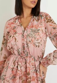 Floral pink dress made of lightweight fabric, featuring ruffle details along the V-neck, elasticated waist, and cuffed long sleeves.