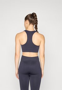 Marine treningsbh med racerback-design og teksturert stoff. Kombinert med matchende høytlivsleggings, med en glatt overflate.