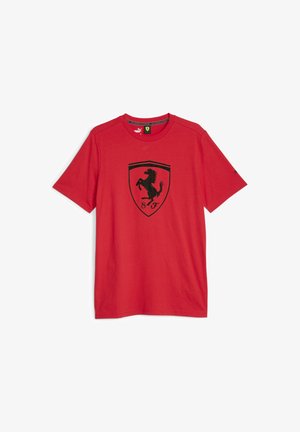 Czerwona bawełniana koszulka z krótkim rękawem z czarnym emblematem skaczącego konia w koronie. Miękka tkanina, casualowy krój.