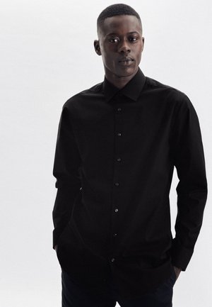 Schwarze Button-Up-Bluse mit langen Ärmeln, aus glattem Stoff gefertigt, mit einem spitzen Kragen und dezenten Knöpfen an der Vorderseite.