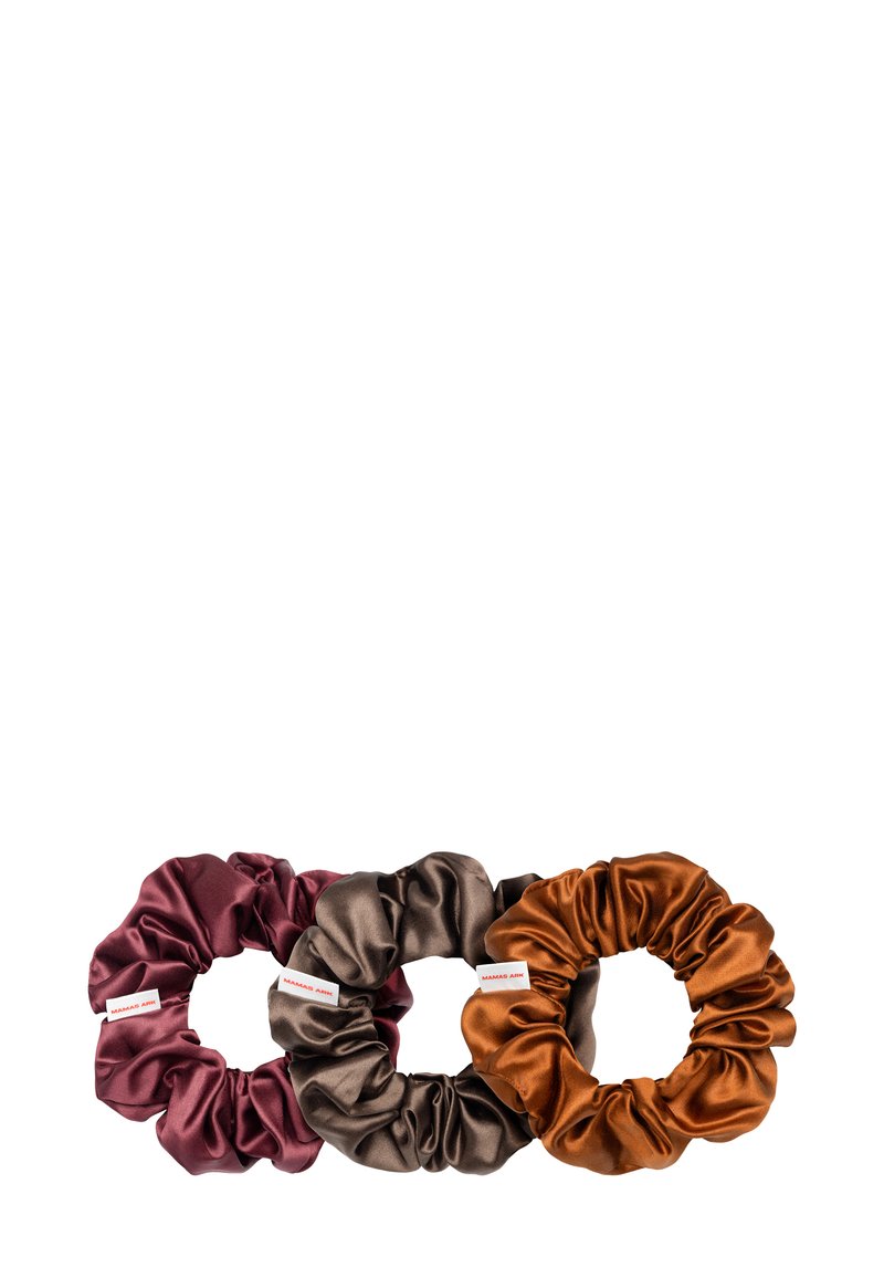 Drie satijnen scrunchies in bordeaux, bruin en roest-oranje. Elke scrunchie heeft een soepele textuur met gegatherde stof en een klein merkembleem.