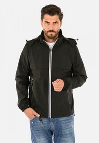 Giacca a vento nera con zip frontale, strisce di accento bianche, cappuccio regolabile e polsini elasticizzati. Vestibilità casual, abbinata a jeans di denim.