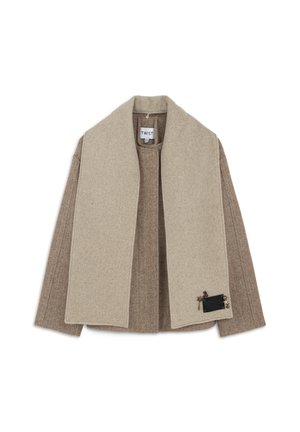 Beige en bruine visgraat wollen jas met een brede beige kraag, voorzien van een decoratieve zwarte zak met accenten aan de linkerkant.