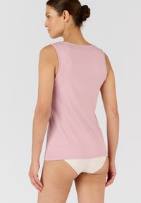 Top in cotone rosa chiaro senza maniche, con scollatura arrotondata. Materiale liscio, forma aderente e schiena pulita e semplice.