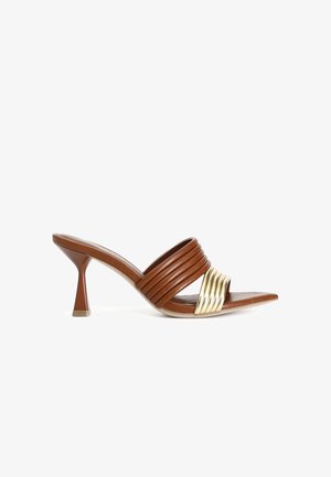 Mule con tacco in pelle marrone con fasce rigate diagonali e accento metallico dorato. Presenta un tacco conico scolpito e una punta appuntita.