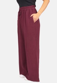 Weite, burgunderfarbene Hosen aus strukturiertem Stoff mit elastischem Bund und Seitentaschen. Bieten eine lockere Passform.