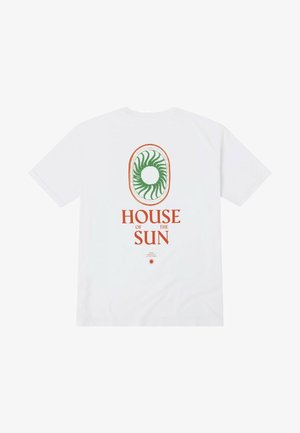 Camiseta de algodón blanca con un gráfico espiral verde en un óvalo y texto naranja que dice "CASA del SOL" en la parte posterior.
