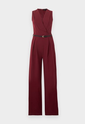 Mouwloze bordeauxrode jumpsuit met wijde pijpen, getailleerde plooien, reverskraag en een smalle zwarte riem met gouden gesp in de taille.