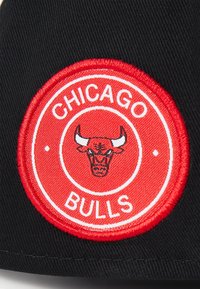 Schwarze Kappe mit einem runden, rot gestickten Patch, der einen Stierkopf und den Text "CHICAGO BULLS" in Weiß zeigt. Glattes, langlebiges Material.