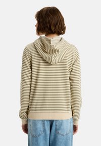 Sudadera con capucha en rayas horizontales de color beige claro y verde oliva, con puños acanalados y un corte relajado. Presenta un detalle en la costura del cuello en la parte posterior.