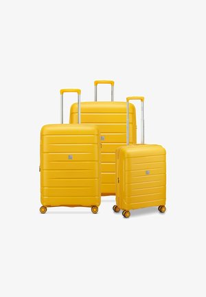 Drei gelbe Hartschalenkoffer mit Teleskopgriffen und vier Rollen, nach Größe auf einem weißen Hintergrund angeordnet.