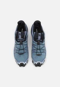 Baskets de course en bleu clair et gris foncé. Elles présentent une tige texturée, des lacets noirs et une semelle extérieure robuste blanche et noire pour une meilleure adhérence.