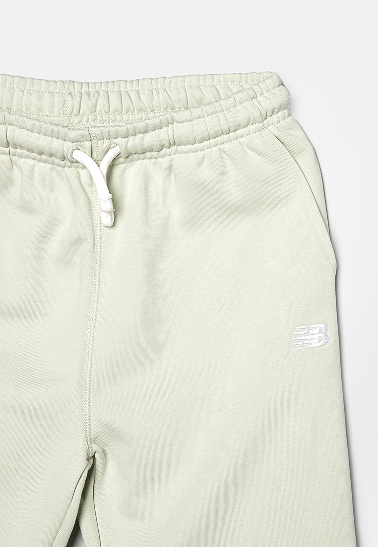Pantaloni della tuta verde chiaro realizzati in morbido tessuto, con vita elastica, lacci bianchi e un piccolo logo bianco sulla gamba.